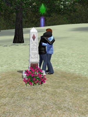A tall tombstone with purple flowers in front of it. To one side, one woman cries on another's shoulder.